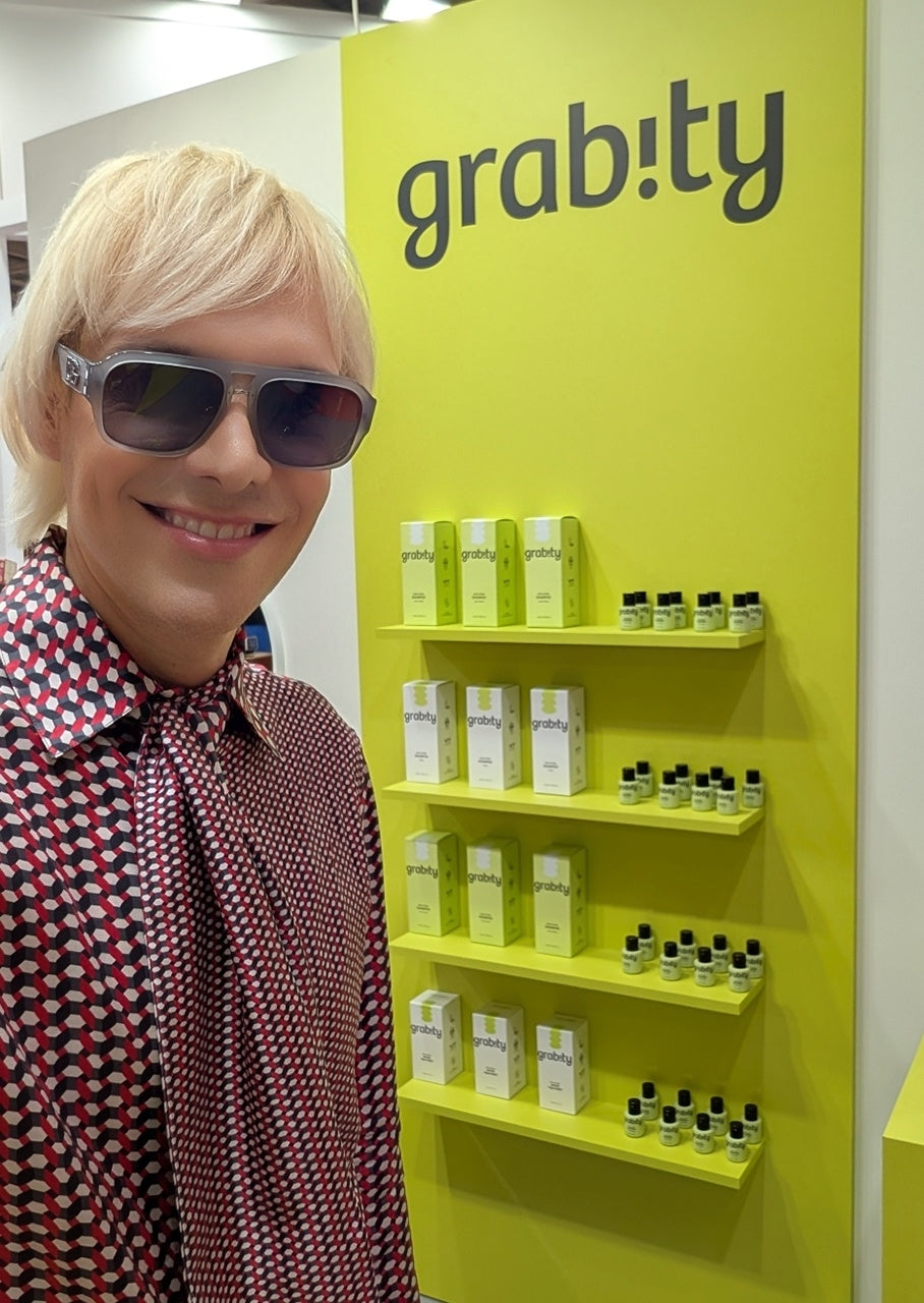 sammy voigt poses in front of a wall with the hair loss shampoo grabity