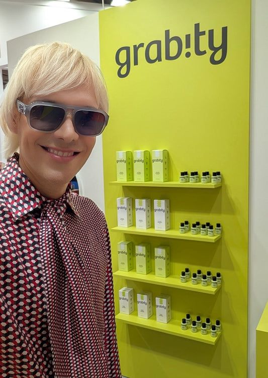 sammy voigt poses in front of a wall with the hair loss shampoo grabity